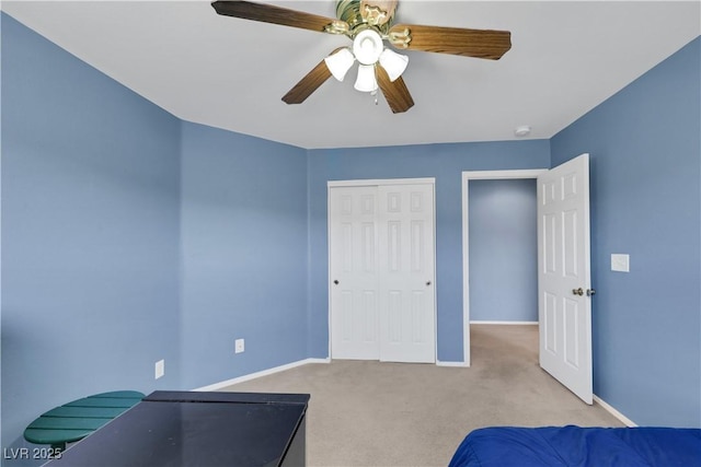 bedroom featuring baseboards, ceiling fan, a closet, and light colored carpet