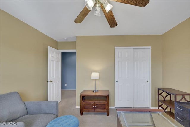 living area featuring baseboards, ceiling fan, and light colored carpet