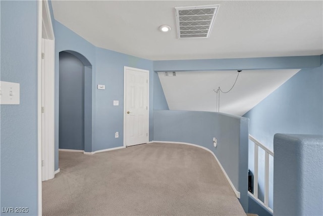 interior space with light colored carpet, visible vents, arched walkways, and baseboards