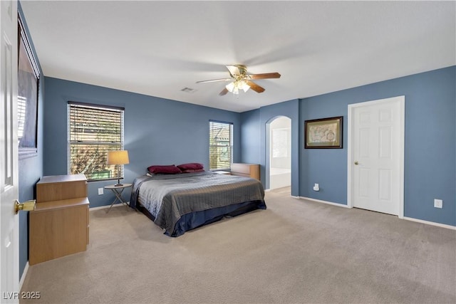 bedroom featuring arched walkways, multiple windows, visible vents, and light colored carpet