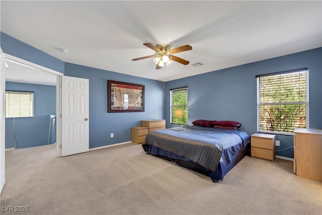 bedroom with light colored carpet, visible vents, ceiling fan, and multiple windows