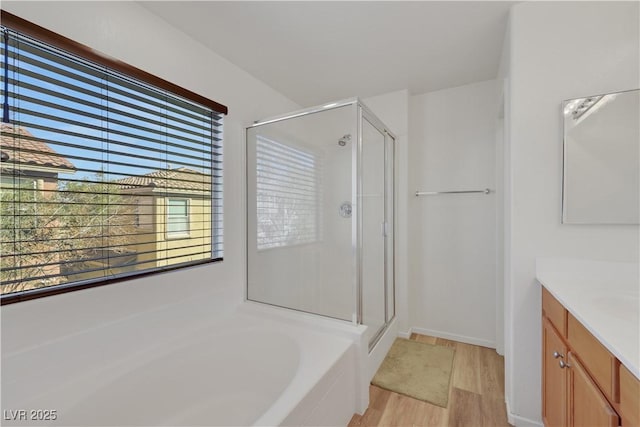 full bath with a stall shower, a garden tub, vanity, and wood finished floors