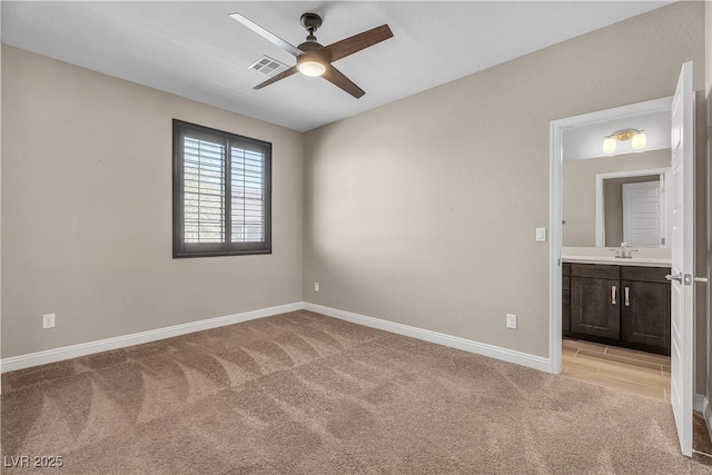 unfurnished room with baseboards, visible vents, a ceiling fan, light colored carpet, and a sink