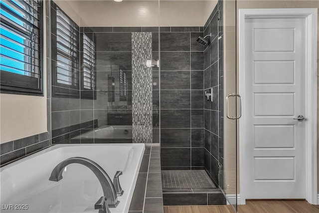 bathroom with a shower stall, a bath, and wood finished floors