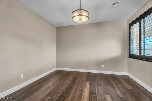 unfurnished room with dark wood-style floors, visible vents, and baseboards