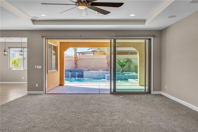 entryway featuring recessed lighting, a ceiling fan, baseboards, a tray ceiling, and carpet