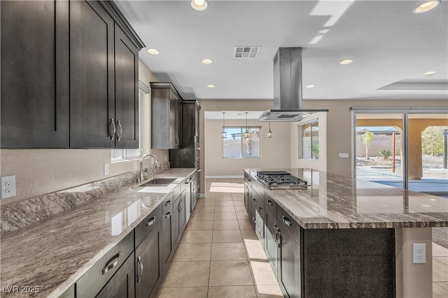 kitchen with visible vents, light tile patterned flooring, a sink, island range hood, and dark stone counters