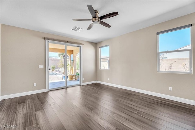 empty room with a ceiling fan, baseboards, visible vents, and dark wood-type flooring