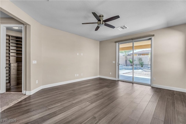 unfurnished room featuring baseboards, visible vents, ceiling fan, and dark wood-style flooring