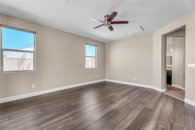 empty room with ceiling fan, dark wood-type flooring, visible vents, and baseboards