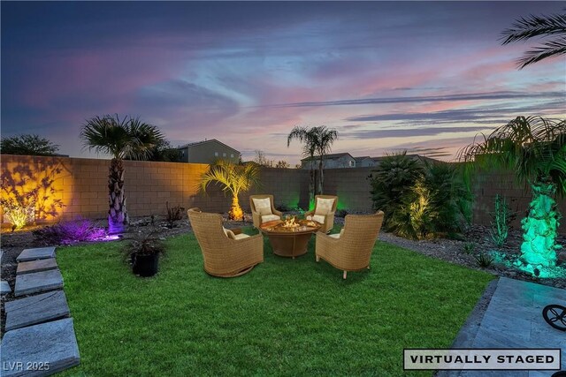 yard at dusk with an outdoor fire pit and a fenced backyard