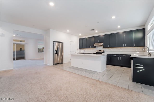 kitchen with light carpet, stainless steel appliances, light countertops, under cabinet range hood, and a sink