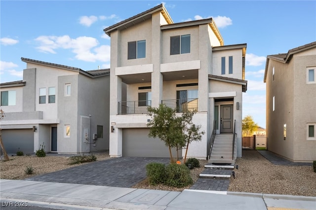 view of front facade with a garage, decorative driveway, a balcony, and stucco siding