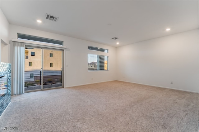 spare room featuring light carpet, visible vents, and recessed lighting