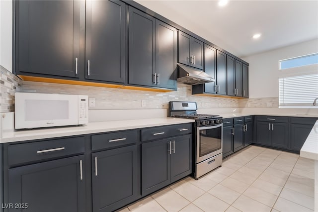 kitchen featuring stainless steel gas range, light countertops, under cabinet range hood, and white microwave