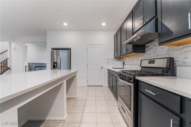 kitchen with under cabinet range hood, decorative backsplash, stainless steel appliances, and light countertops