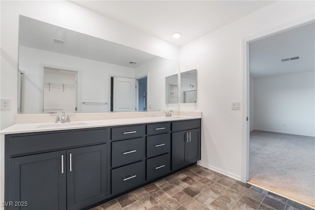 bathroom featuring visible vents, a sink, baseboards, and double vanity