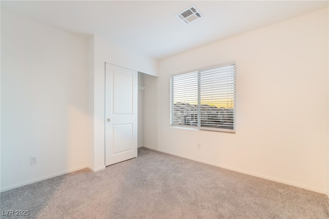 unfurnished bedroom featuring a closet, visible vents, light carpet, and baseboards