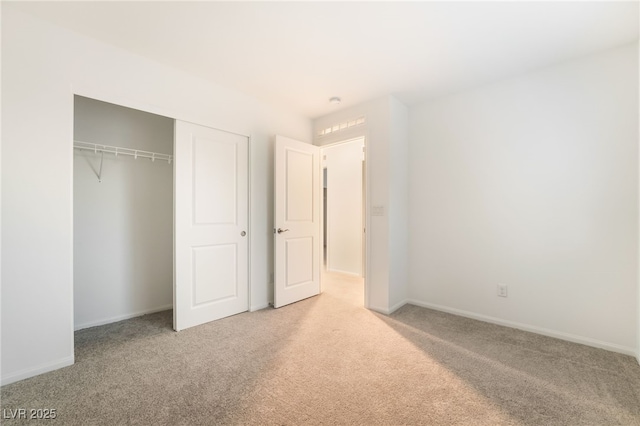 unfurnished bedroom with a closet, light carpet, and baseboards