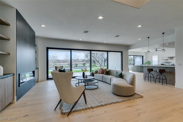 living room featuring light wood-type flooring, plenty of natural light, and recessed lighting