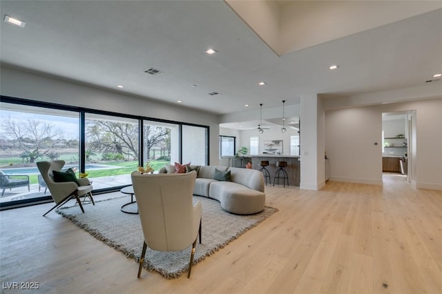 living area with light wood-style floors, recessed lighting, visible vents, and baseboards