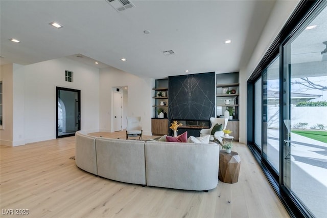 living room featuring built in shelves, recessed lighting, visible vents, baseboards, and light wood-type flooring