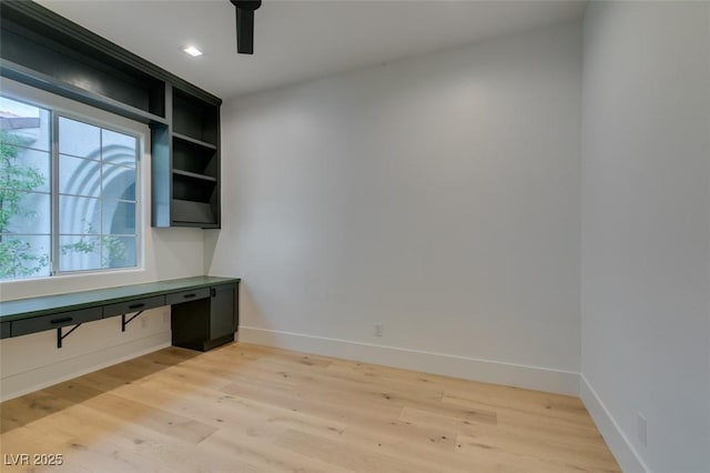 unfurnished office featuring light wood finished floors, a ceiling fan, and baseboards