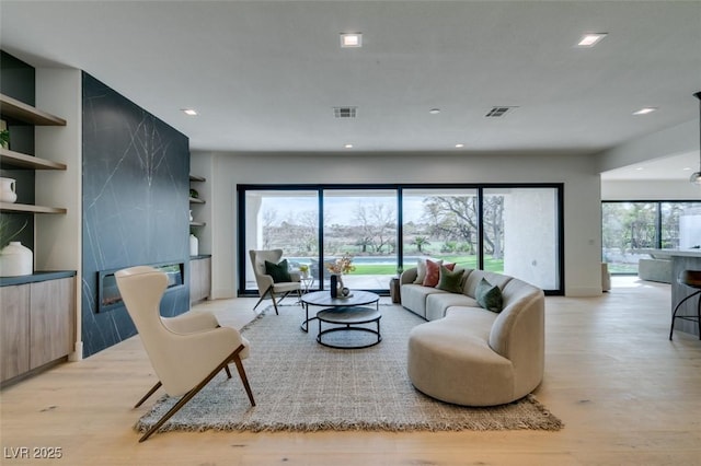 living area featuring built in features, a fireplace, recessed lighting, visible vents, and light wood-type flooring