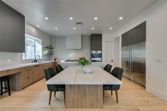 kitchen featuring a spacious island, modern cabinets, appliances with stainless steel finishes, a kitchen breakfast bar, and a sink