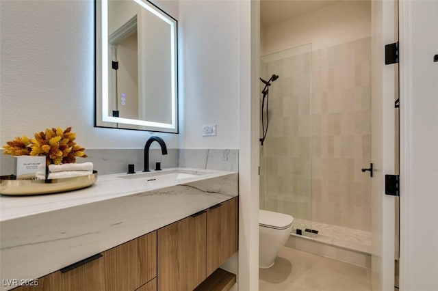 bathroom with toilet, a tile shower, and vanity