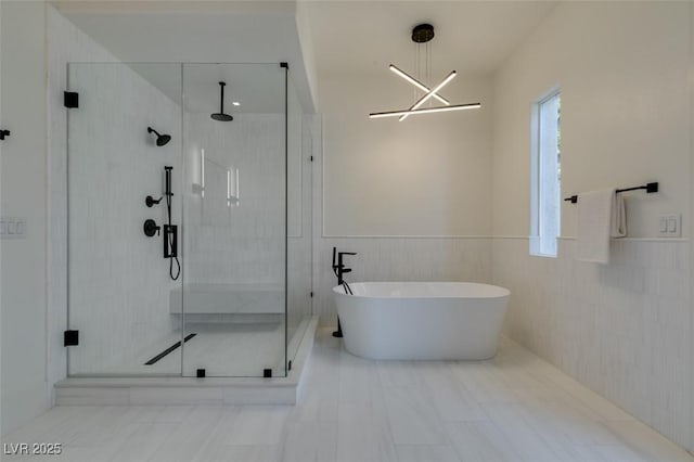 full bath with a wainscoted wall, a stall shower, a freestanding tub, and tile walls