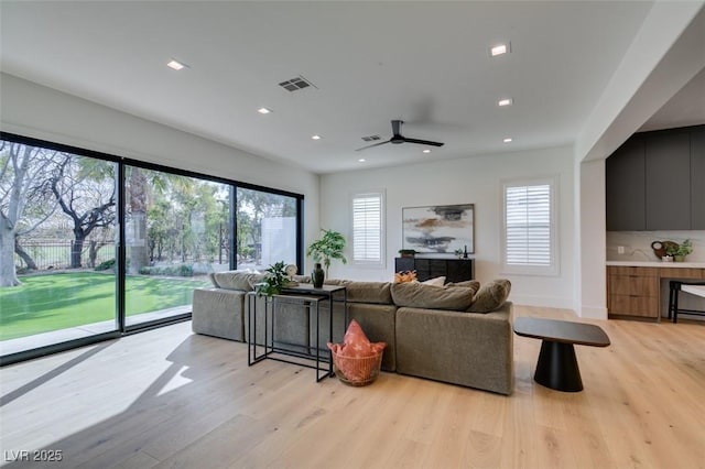 living room featuring baseboards, recessed lighting, visible vents, and light wood-style floors