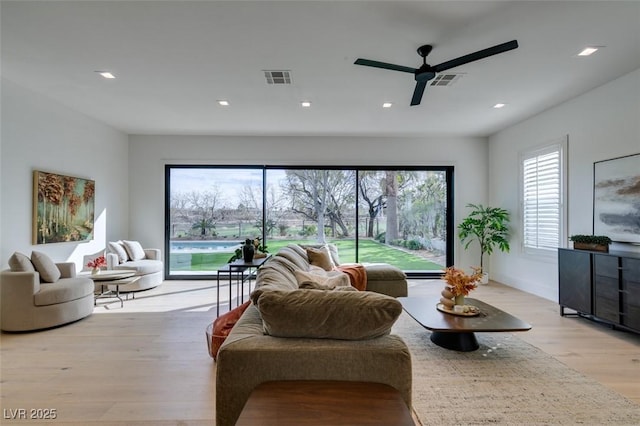 living room featuring light wood-style flooring, a ceiling fan, visible vents, and recessed lighting