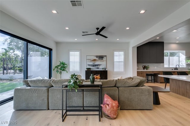 living area with light wood finished floors, visible vents, and recessed lighting