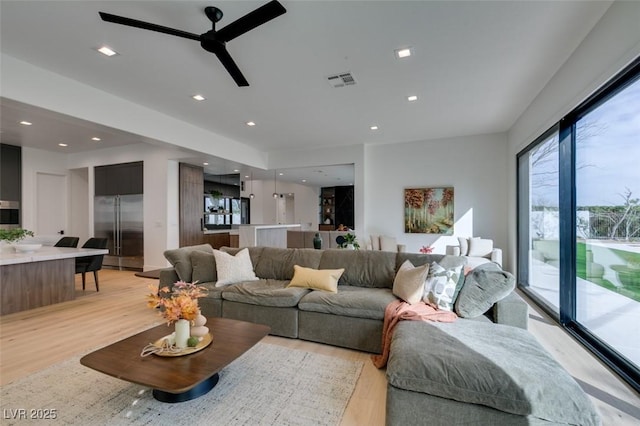 living area featuring a ceiling fan, light wood-type flooring, visible vents, and recessed lighting