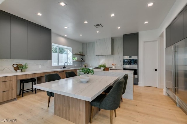 kitchen featuring a kitchen breakfast bar, premium range hood, built in refrigerator, and modern cabinets