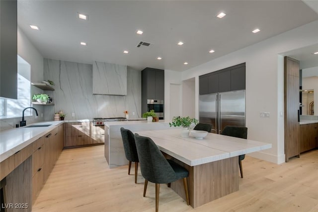 kitchen with a large island, open shelves, stainless steel appliances, a sink, and modern cabinets