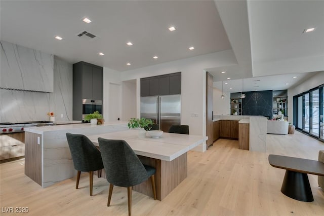 kitchen with appliances with stainless steel finishes, a spacious island, modern cabinets, and visible vents