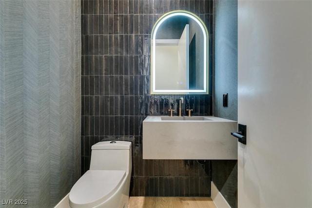 full bathroom featuring a sink, toilet, and tile walls