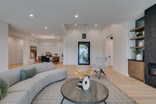 living room featuring recessed lighting, baseboards, and light wood finished floors