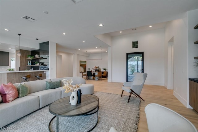 living area featuring baseboards, recessed lighting, visible vents, and light wood-style floors