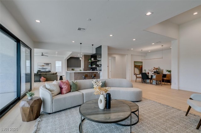 living area with baseboards, light wood-type flooring, visible vents, and recessed lighting