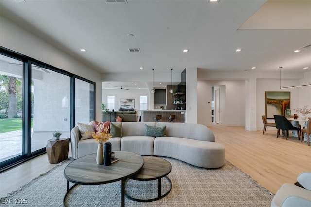 living room featuring recessed lighting, visible vents, light wood-style flooring, and baseboards