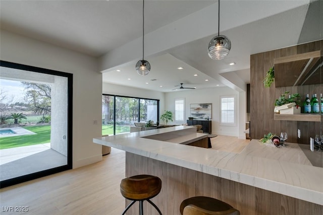 kitchen featuring light wood-style flooring, a breakfast bar area, a wealth of natural light, and decorative light fixtures