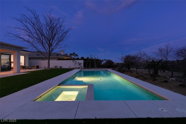 pool at dusk with a patio area, a lawn, a fenced backyard, and an in ground hot tub