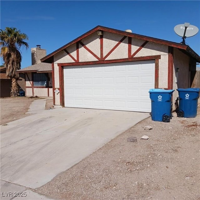 view of front of house with driveway, an attached garage, a chimney, and stucco siding