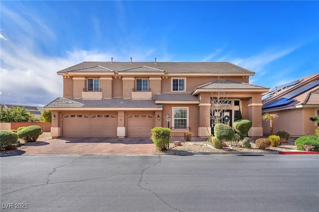 view of front of house featuring decorative driveway, a tiled roof, an attached garage, and stucco siding