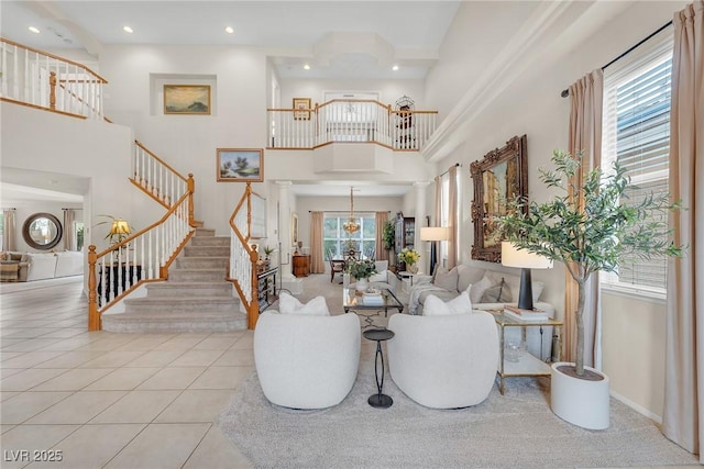 entrance foyer with a towering ceiling, ornate columns, stairway, and tile patterned floors