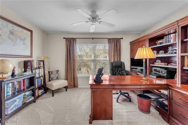 carpeted office with a ceiling fan