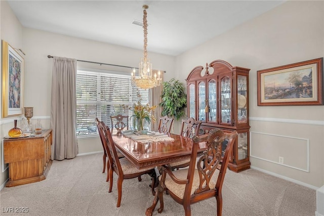 dining room with a chandelier, light colored carpet, visible vents, and baseboards